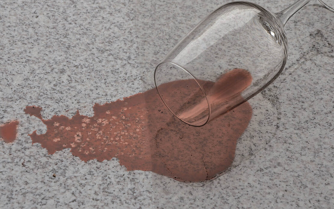 Liegendes Rotweinglas auf halbseitig imprägnierter Oberfläche